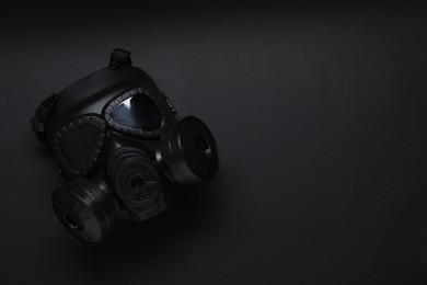 Photo of One gas mask on black background, top view and space for text. Safety equipment