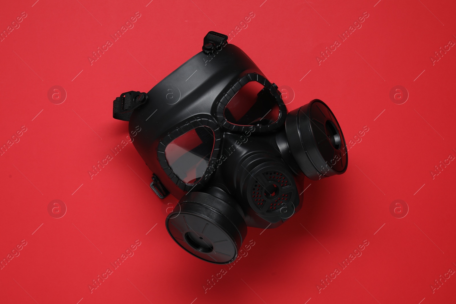 Photo of One gas mask on red background, top view