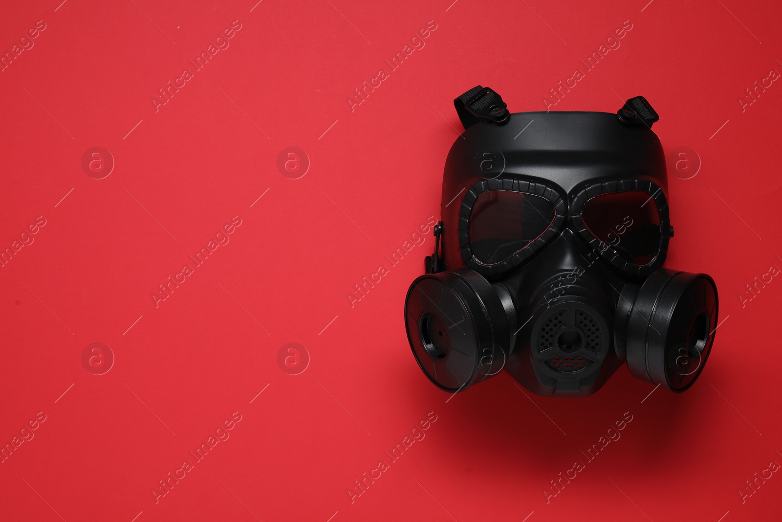 Photo of One gas mask on red background, top view. Space for text