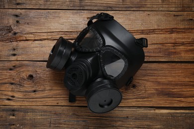 Photo of One gas mask on wooden table, top view