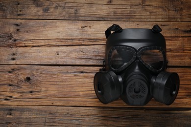 Photo of One gas mask on wooden table, top view. Space for text