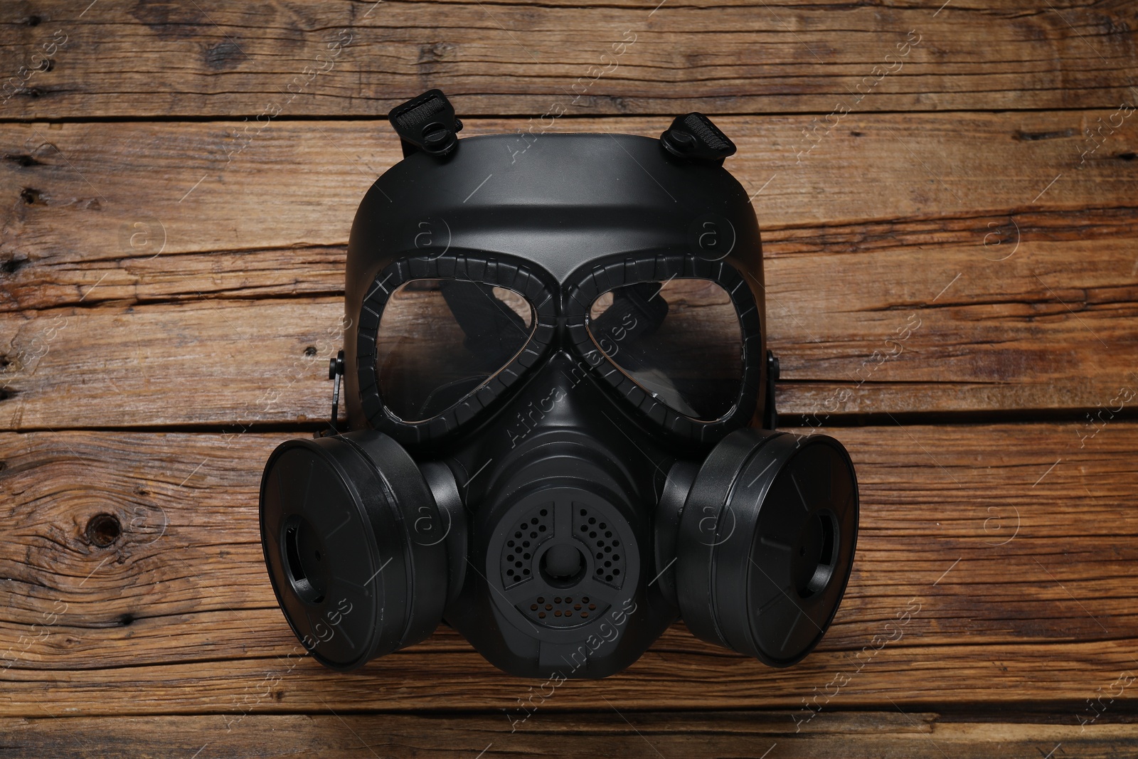 Photo of One gas mask on wooden table, top view