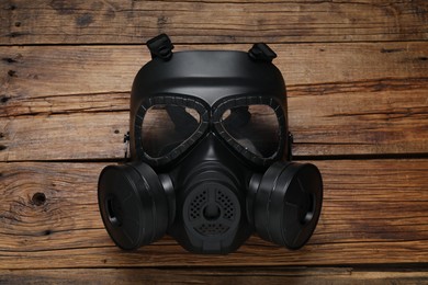 One gas mask on wooden table, top view