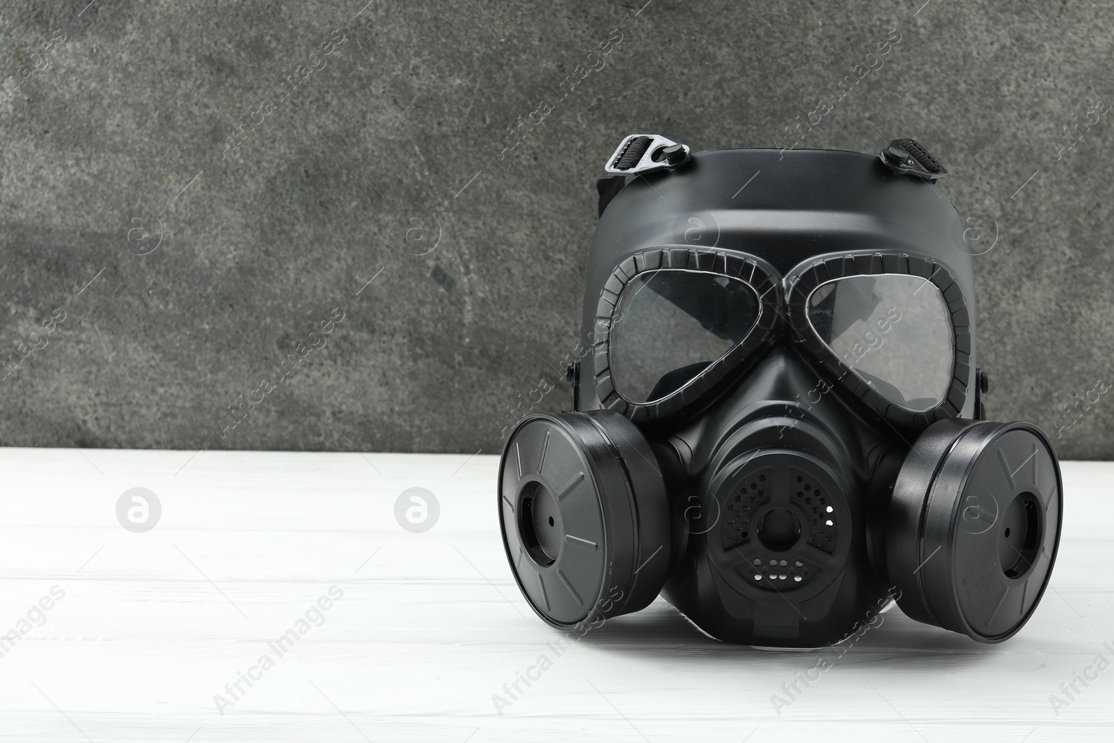Photo of One gas mask on white wooden table, space for text. Safety equipment