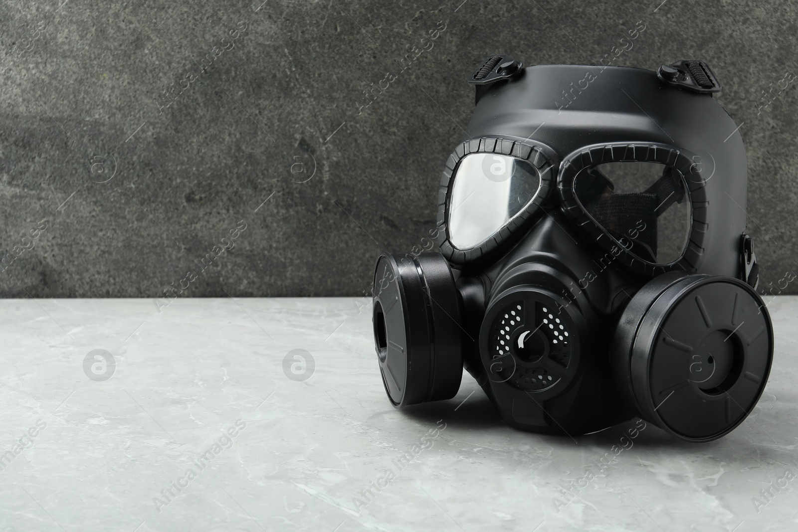 Photo of One gas mask on grey table, space for text. Safety equipment