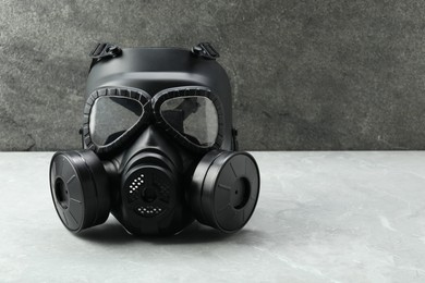One gas mask on grey table, space for text. Safety equipment