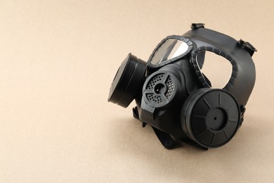 One gas mask on beige background, space for text. Safety equipment