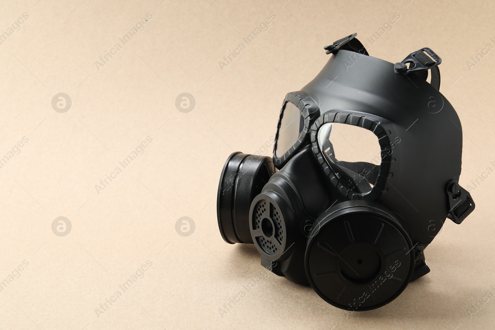 Photo of One gas mask on beige background, space for text. Safety equipment