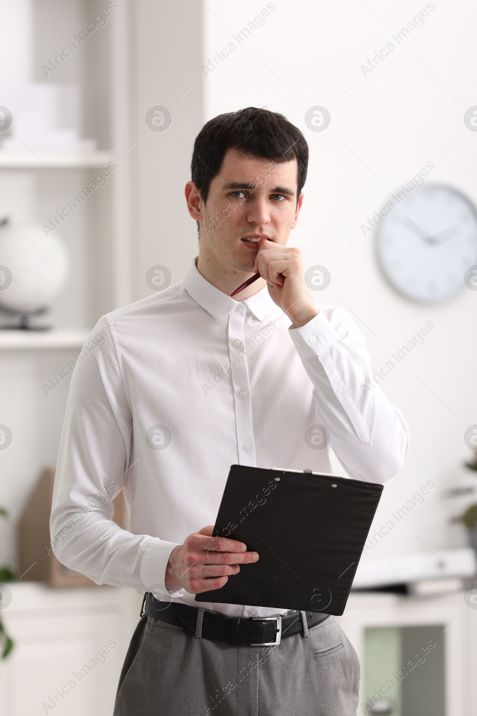 Photo of Embarrassed man with clipboard and pen in office