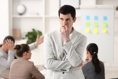 Man feeling embarrassed during business meeting in office