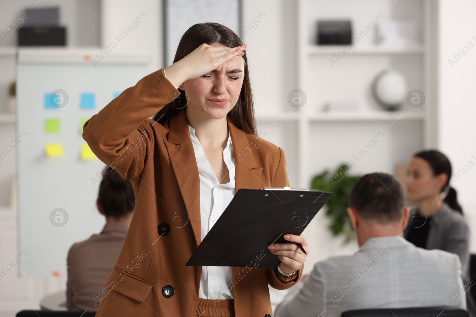 Photo of Woman with clipboard feeling embarrassed during business meeting in office