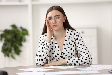 Embarrassed woman in glasses at table in office