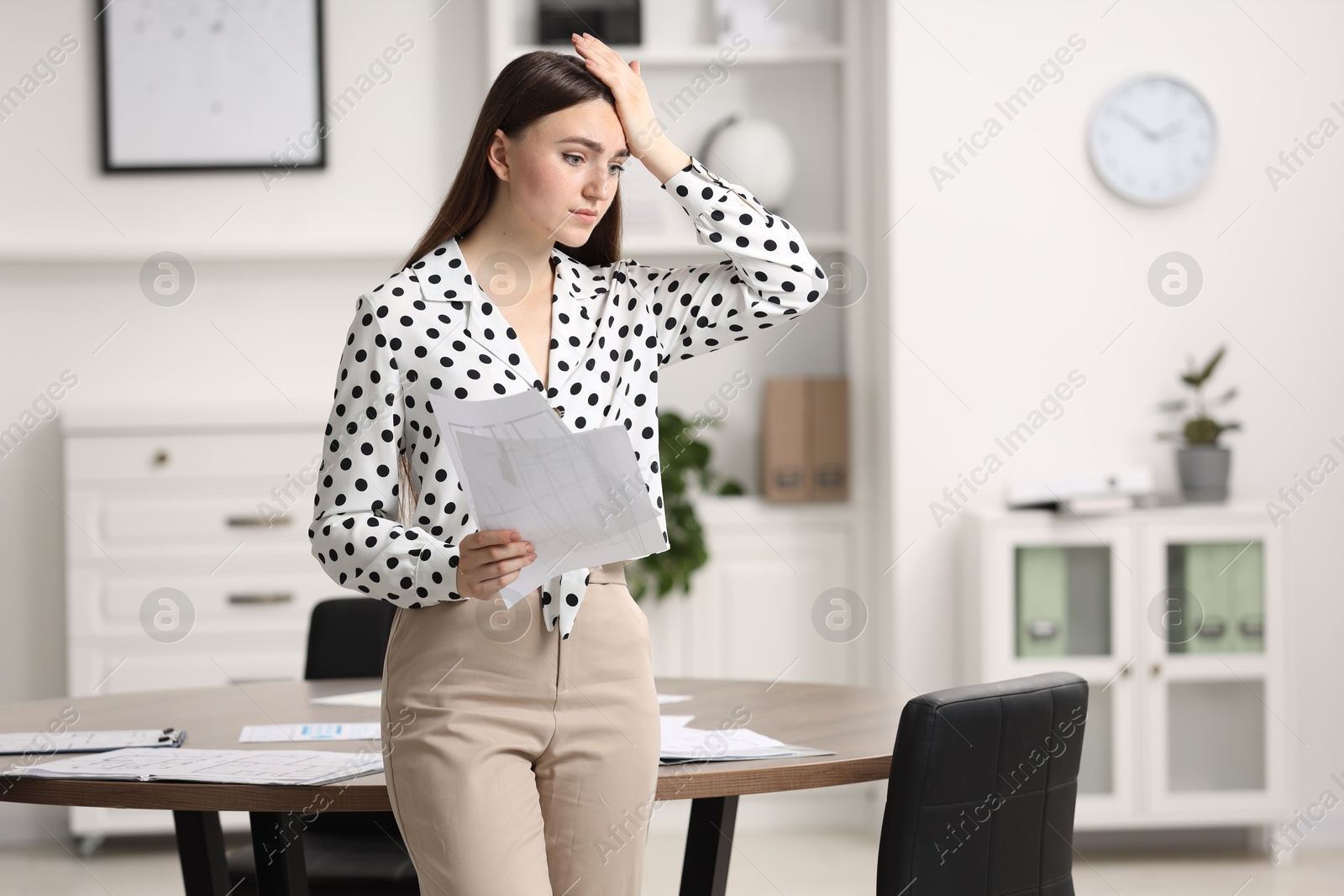 Photo of Embarrassed woman with documents in office, space for text