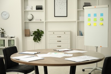 Photo of Wooden table, chairs and white board with sticky notes in conference room