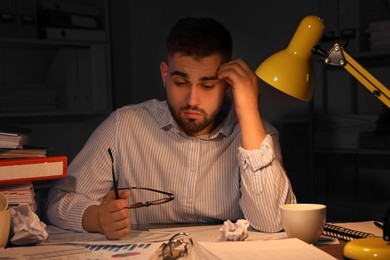 Overwhelmed man at workplace in office at night