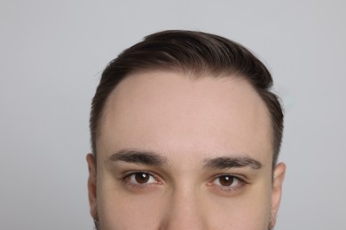 Photo of Baldness concept. Man with receding hairline on light grey background, closeup