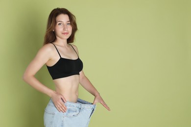 Woman in big jeans showing her slim body on olive background, space for text