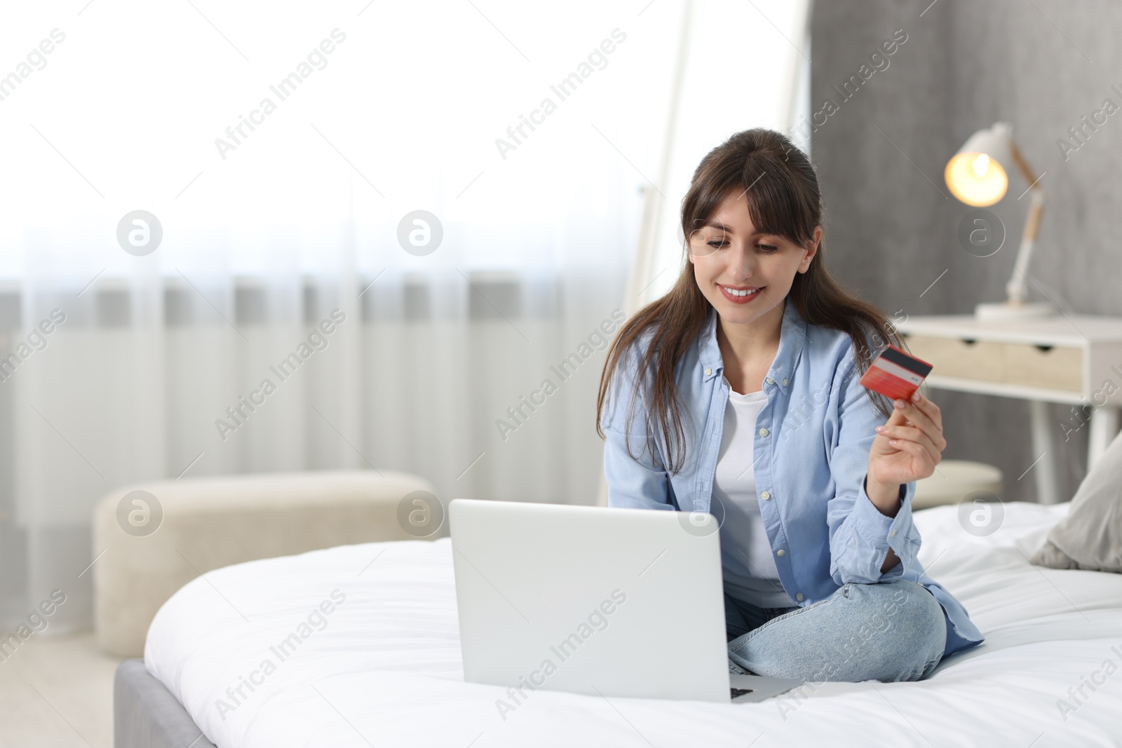 Photo of Online banking. Smiling woman with credit card and laptop paying purchase at home. Space for text