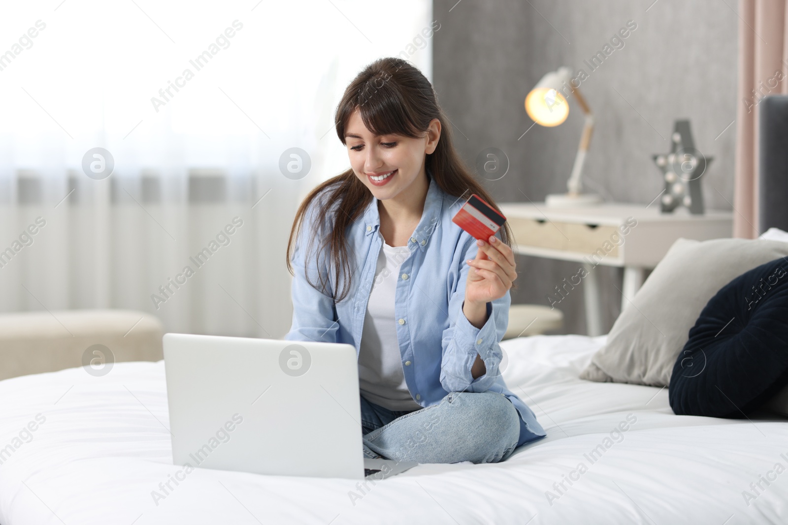 Photo of Online banking. Smiling woman with credit card and laptop paying purchase at home