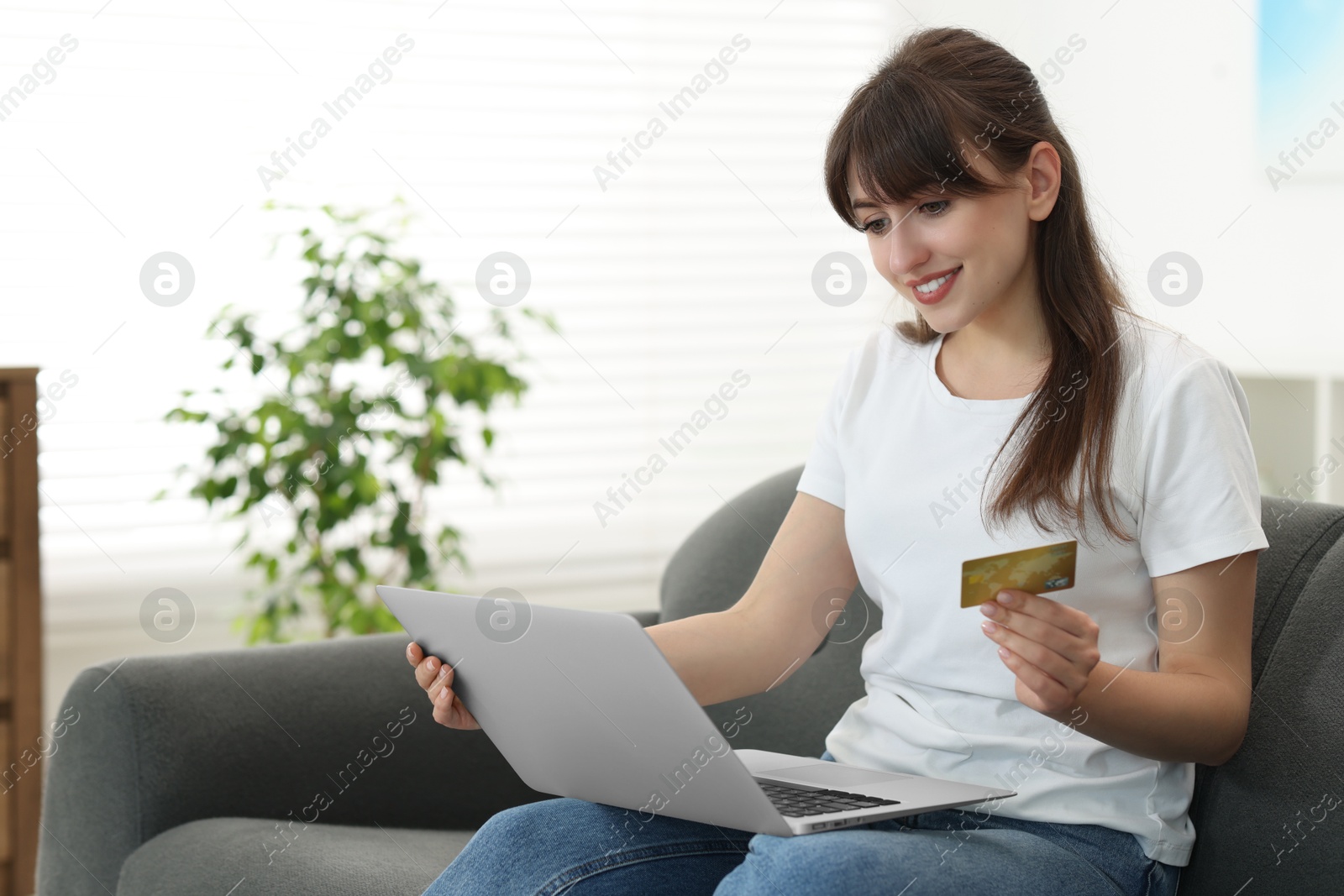 Photo of Online banking. Smiling woman with credit card and laptop paying purchase at home