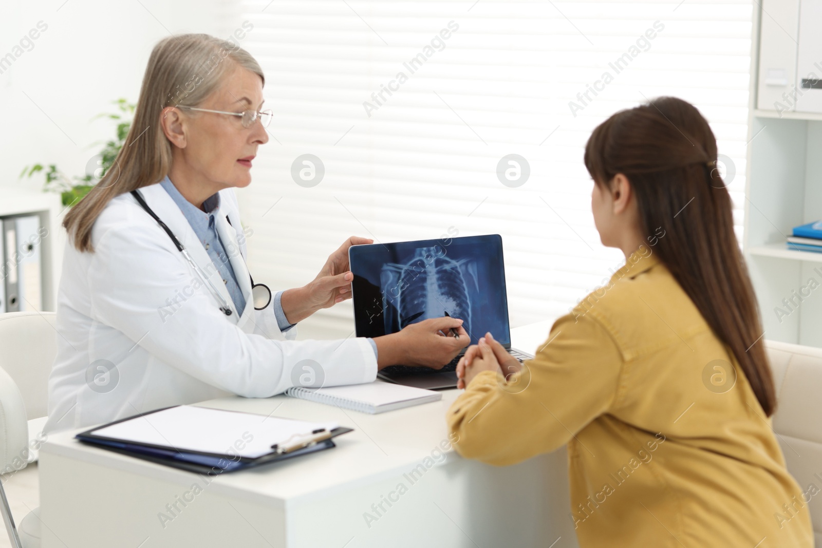 Photo of Lung cancer. Doctor showing chest x-ray on laptop to her patient in clinic