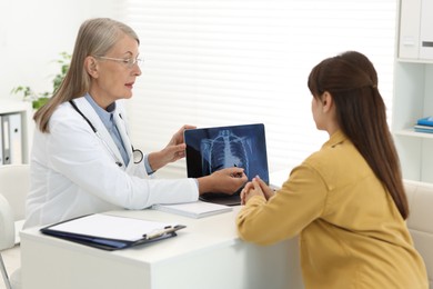 Photo of Lung cancer. Doctor showing chest x-ray on laptop to her patient in clinic