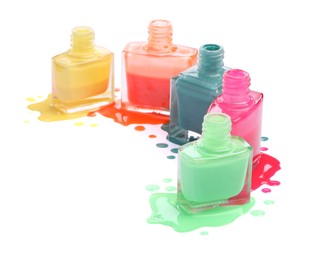 Many bottles and drops of colorful nail polishes isolated on white