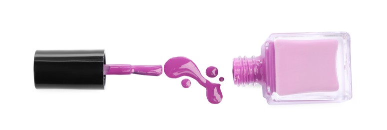 Bottle, brush and spilled purple nail polish isolated on white, top view