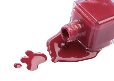 Photo of Bottle and spilled red nail polish isolated on white