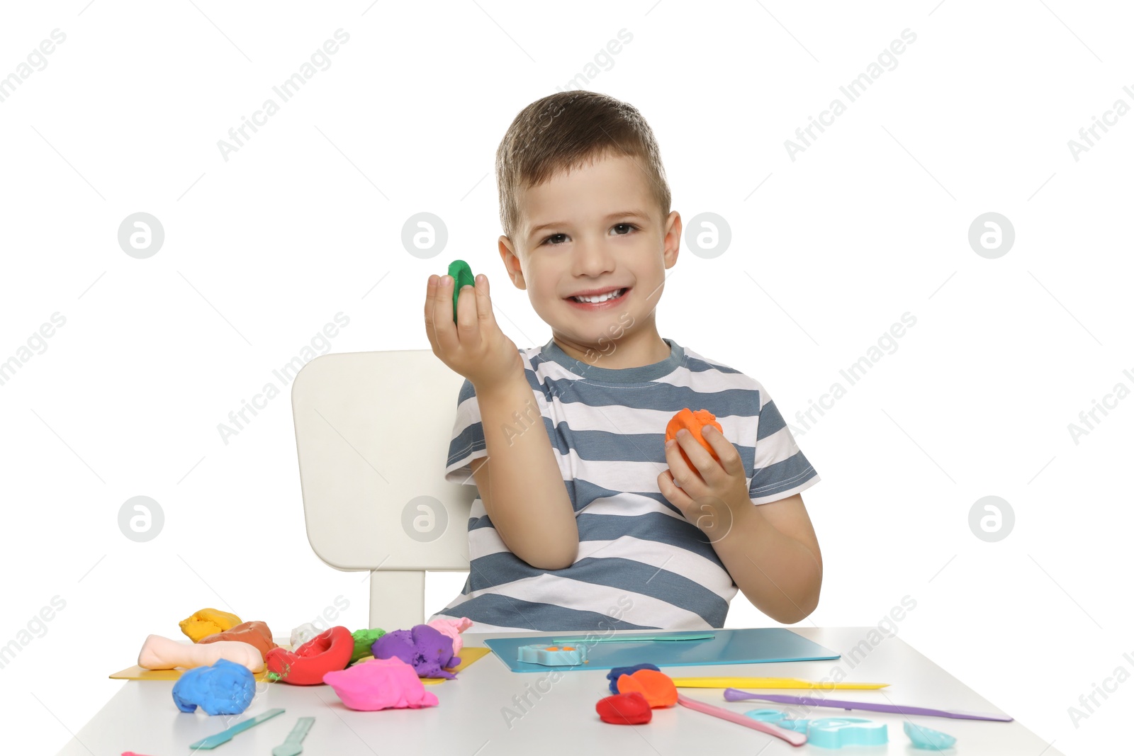 Photo of Smiling boy with play dough handiwork at table on white background