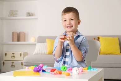 Photo of Smiling boy sculpting with play dough at table in kindergarten