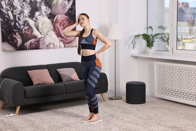 Photo of Worried woman standing on floor scale at home