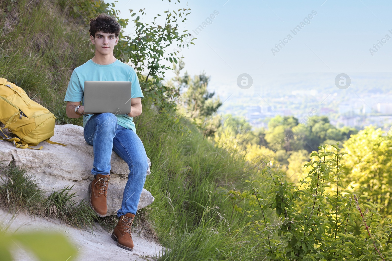 Photo of Travel blogger using laptop on stone outdoors, space for text