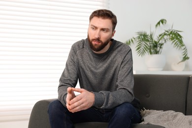 Photo of Loneliness concept. Sad man sitting on sofa at home