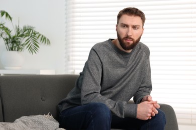 Photo of Loneliness concept. Sad man sitting on sofa at home