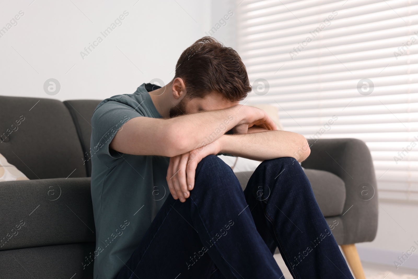 Photo of Loneliness concept. Sad man sitting on floor at home