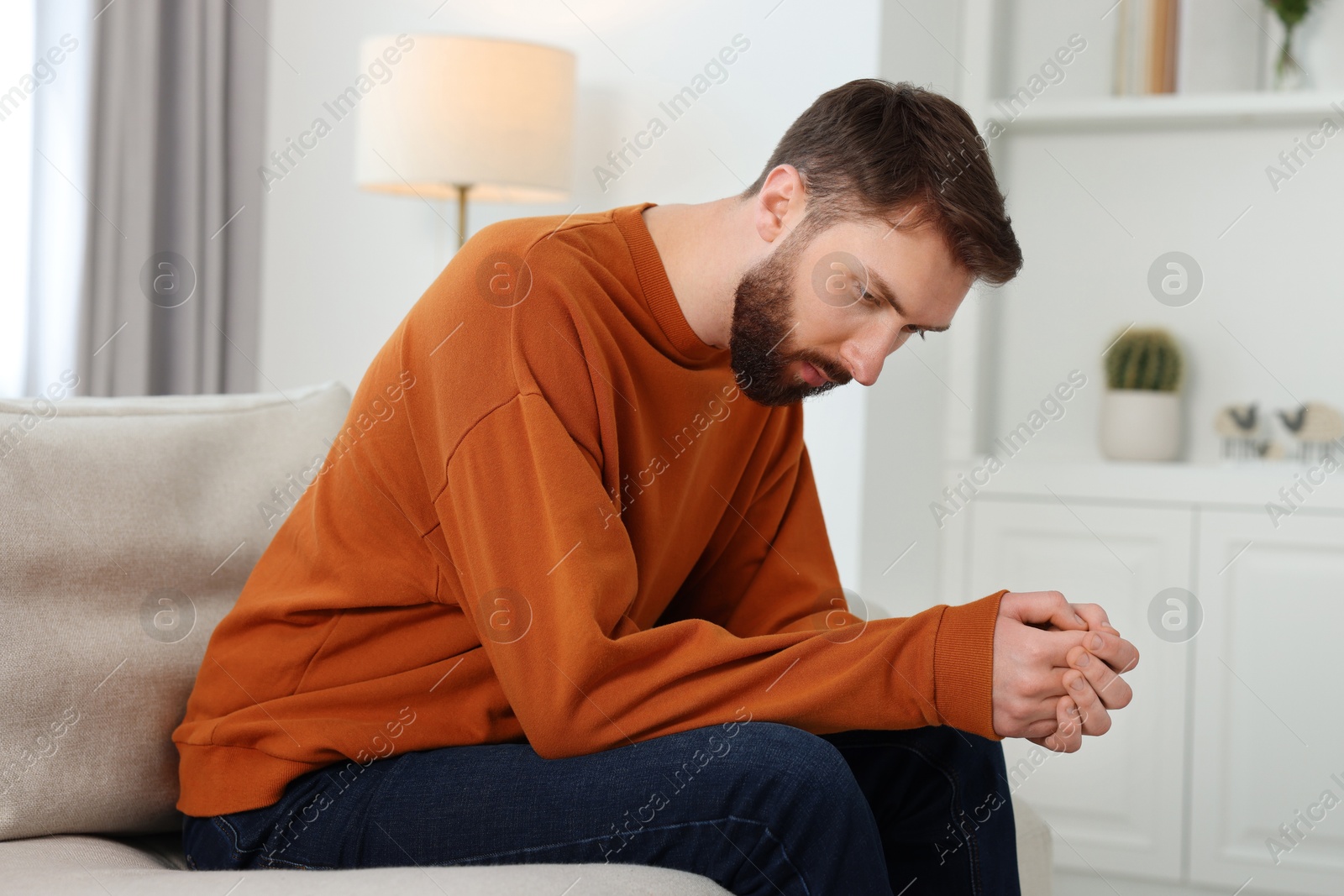 Photo of Loneliness concept. Sad man sitting on sofa at home