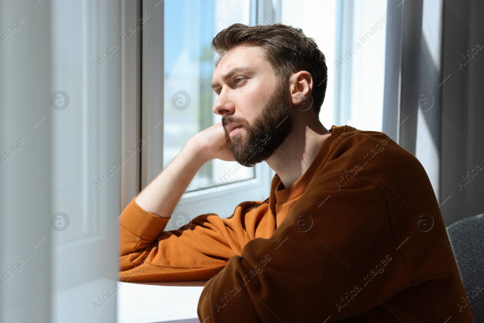 Photo of Loneliness concept. Sad man near window at home