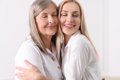 Family portrait of young woman and her mother near white wall
