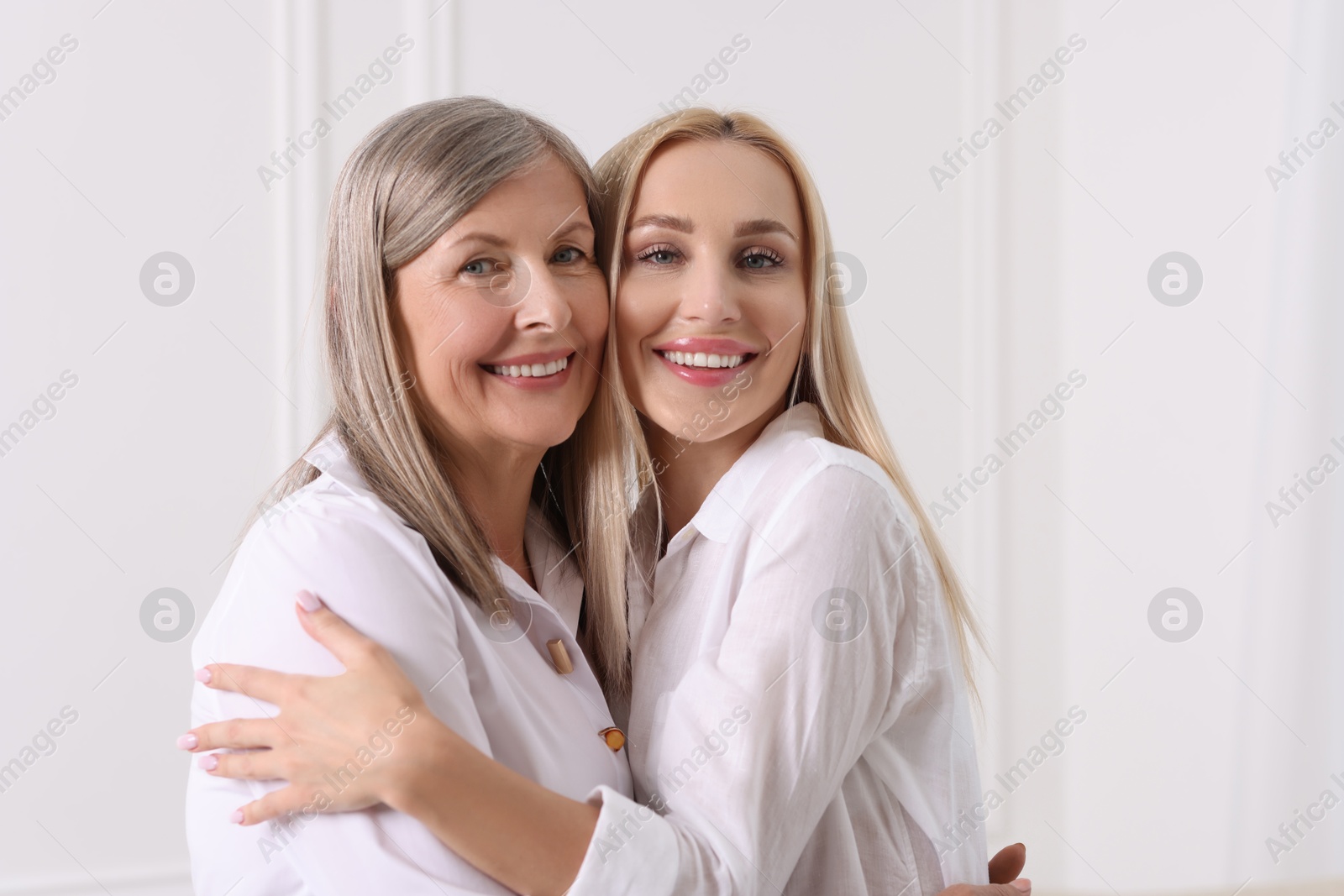 Photo of Family portrait of young woman and her mother near white wall