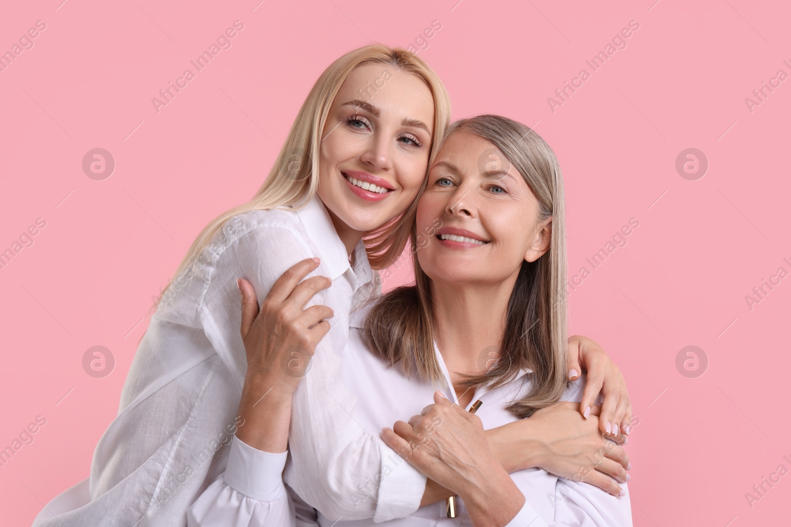 Photo of Family portrait of young woman and her mother on pink background