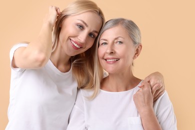 Family portrait of young woman and her mother on beige background