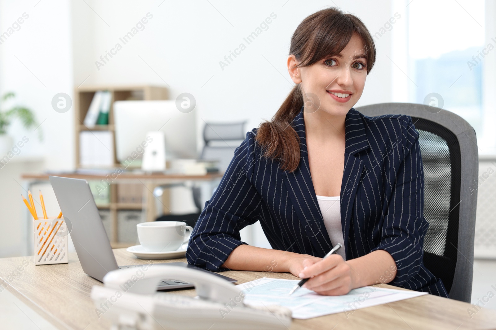 Photo of Portrait of smiling secretary at table in office