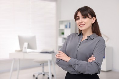 Photo of Portrait of smiling secretary with crossed arms in office. Space for text