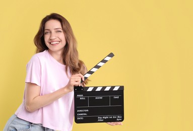 Making movie. Smiling woman with clapperboard on yellow background. Space for text