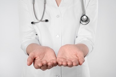 Photo of Doctor holding something on light grey background, closeup
