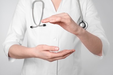 Doctor holding something on light grey background, closeup