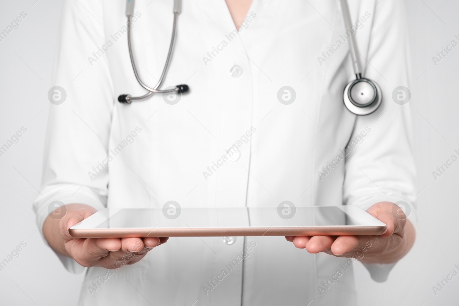 Photo of Doctor with tablet on light grey background, closeup