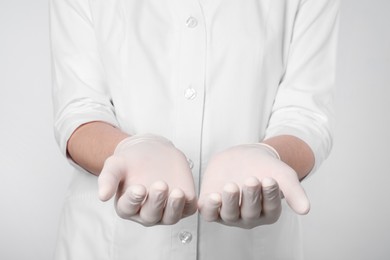 Doctor holding something on light grey background, closeup