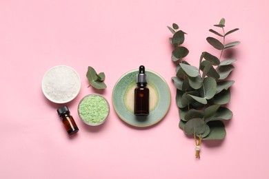 Aromatherapy products. Bottles of essential oil, sea salt and eucalyptus leaves on pink background, flat lay